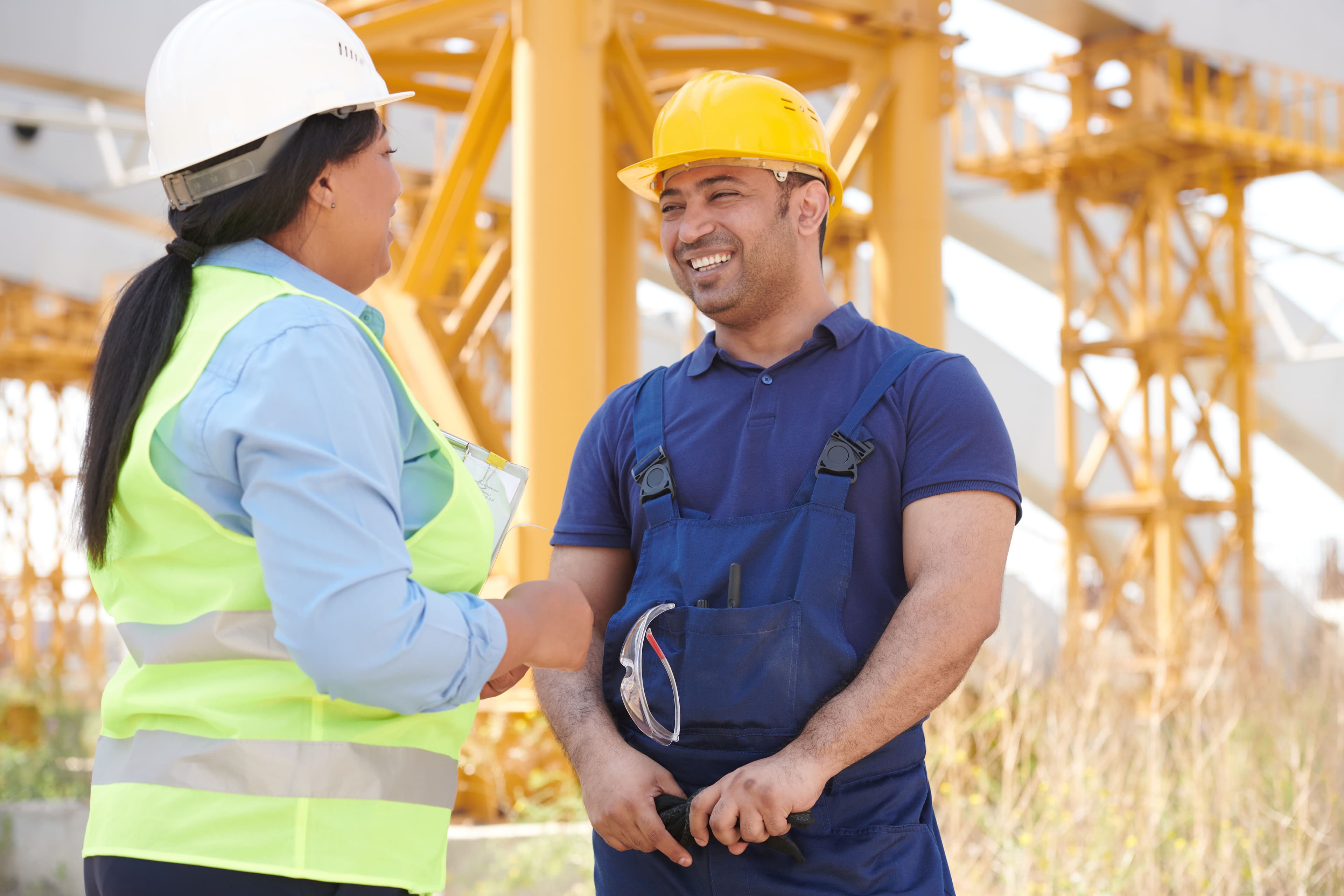 A construction supervisor and worker greeting each other on site